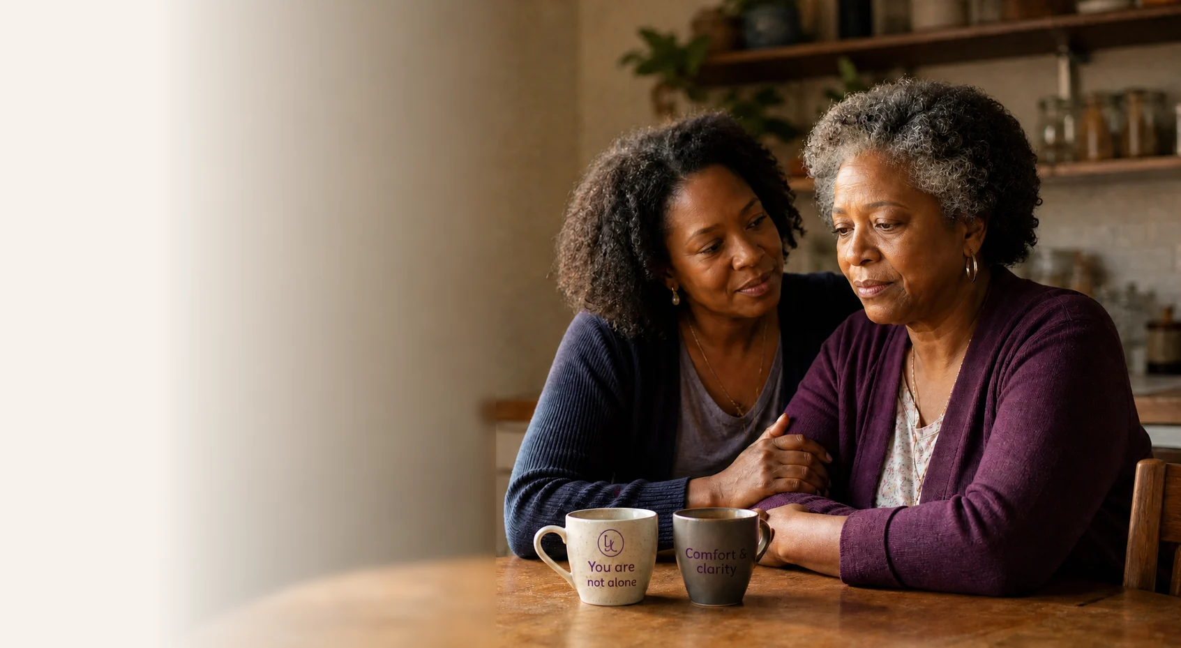 A caregiver being comforted by a peer at her kitchen table